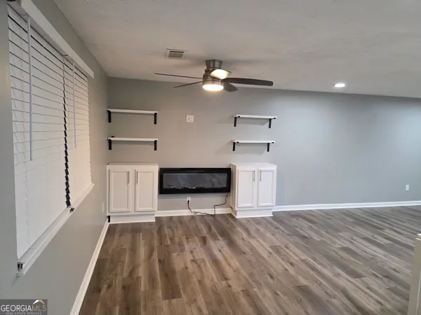 a view of a kitchen with wooden floor a ceiling fan and refrigerator