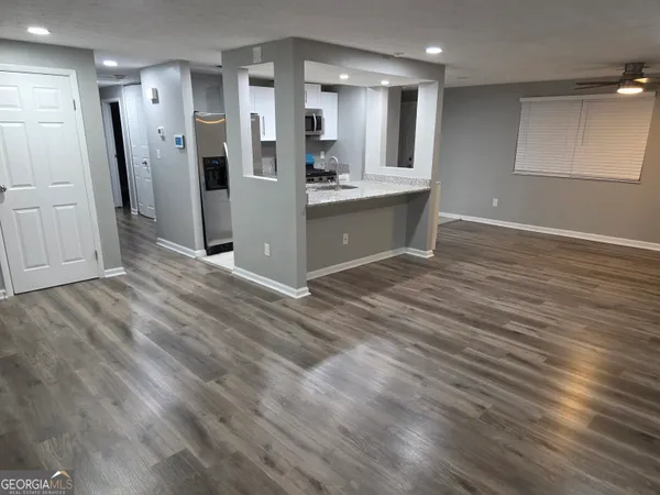 an empty room with wooden floor and kitchen view
