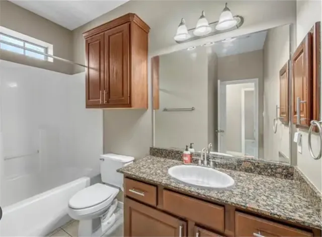 a bathroom with a granite countertop sink a toilet a mirror and shower