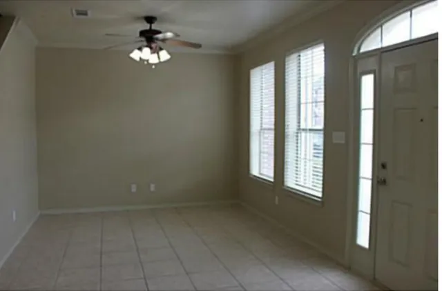 en empty room with windows and chandelier fan
