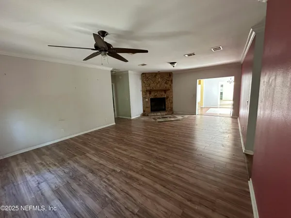 a view of an empty room with kitchen and a window