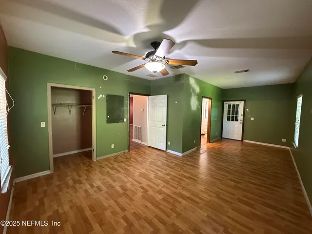 a view of an empty room with window and wooden floor