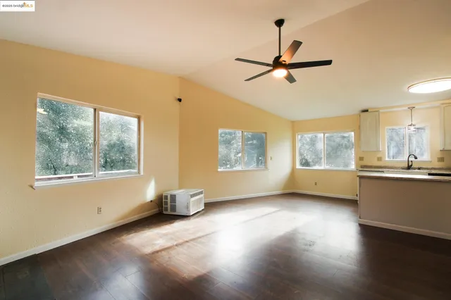 a view of an empty room with a window and wooden floor