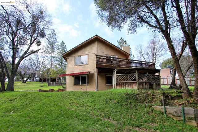 a view of a house with a yard and large trees