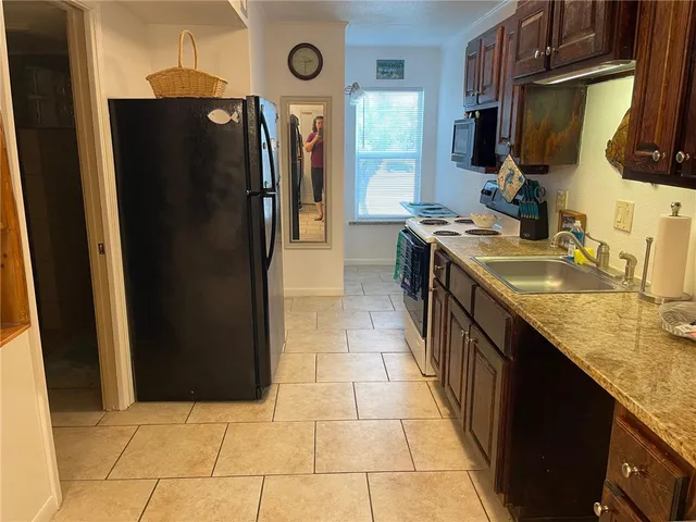 a kitchen with stainless steel appliances granite countertop a refrigerator a stove and a sink