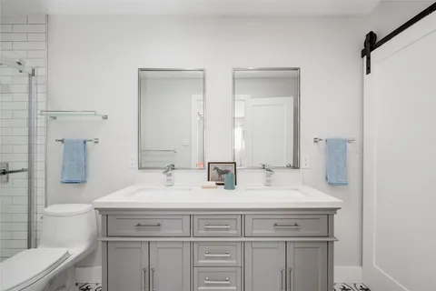 a bathroom with a double vanity sink toilet and a mirror