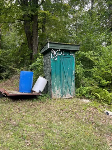 a backyard of a house with large trees and wooden fence