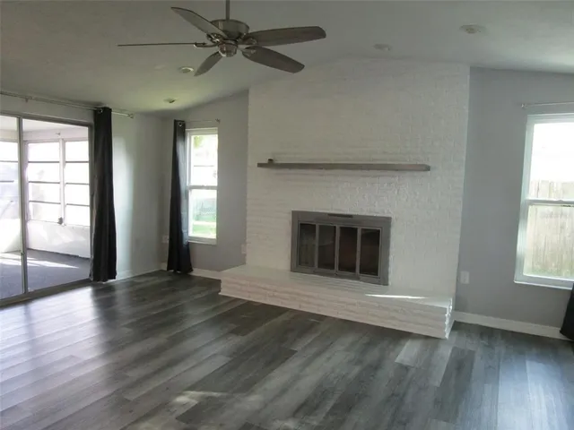 an empty room with wooden floor a ceiling fan and windows