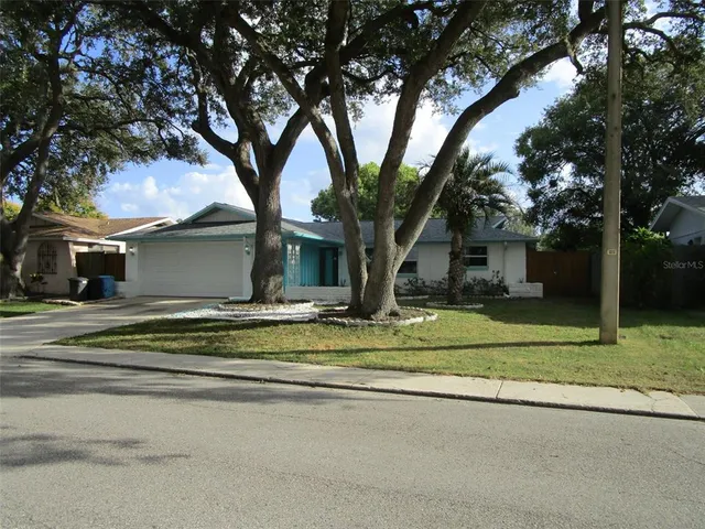 a view of a house with a yard and large trees