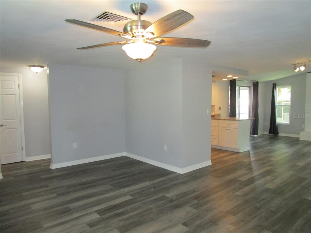 7226 San Moritz Drive Port Richey, FL 34668 - Photo 23 of 38 an empty room with wooden floor chandelier fan and windows