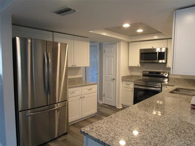 a kitchen with granite countertop a refrigerator stove and microwave