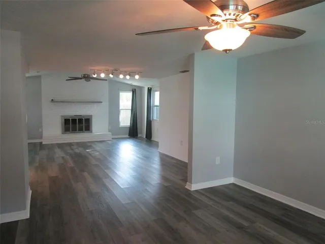 a view of a livingroom with a fireplace a chandelier fan and wooden floor