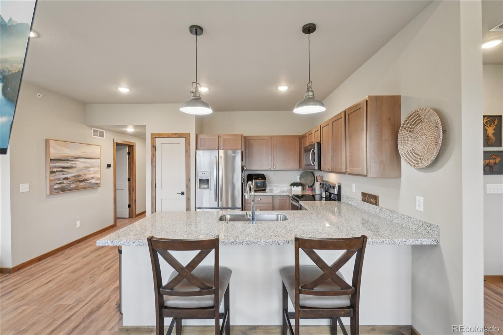 1700 Wildfire Road, Unit 301 Estes Park, CO 80517 - Photo 13 of 38 a kitchen with stainless steel appliances kitchen island granite countertop a dining table chairs and a refrigerator
