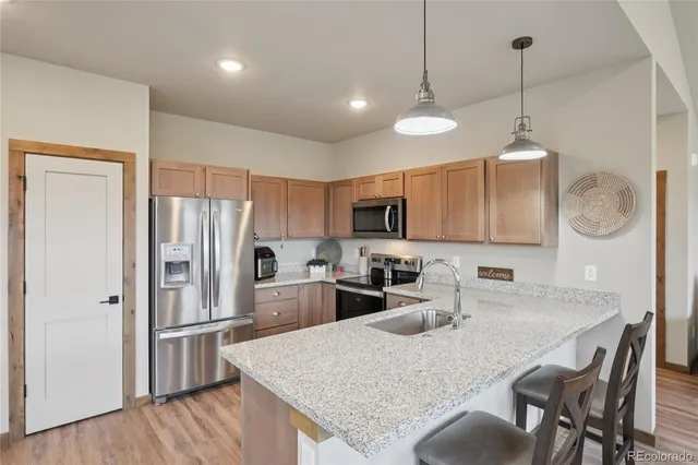 a kitchen with stainless steel appliances granite countertop a refrigerator a sink dishwasher a oven with white cabinets and wooden floor