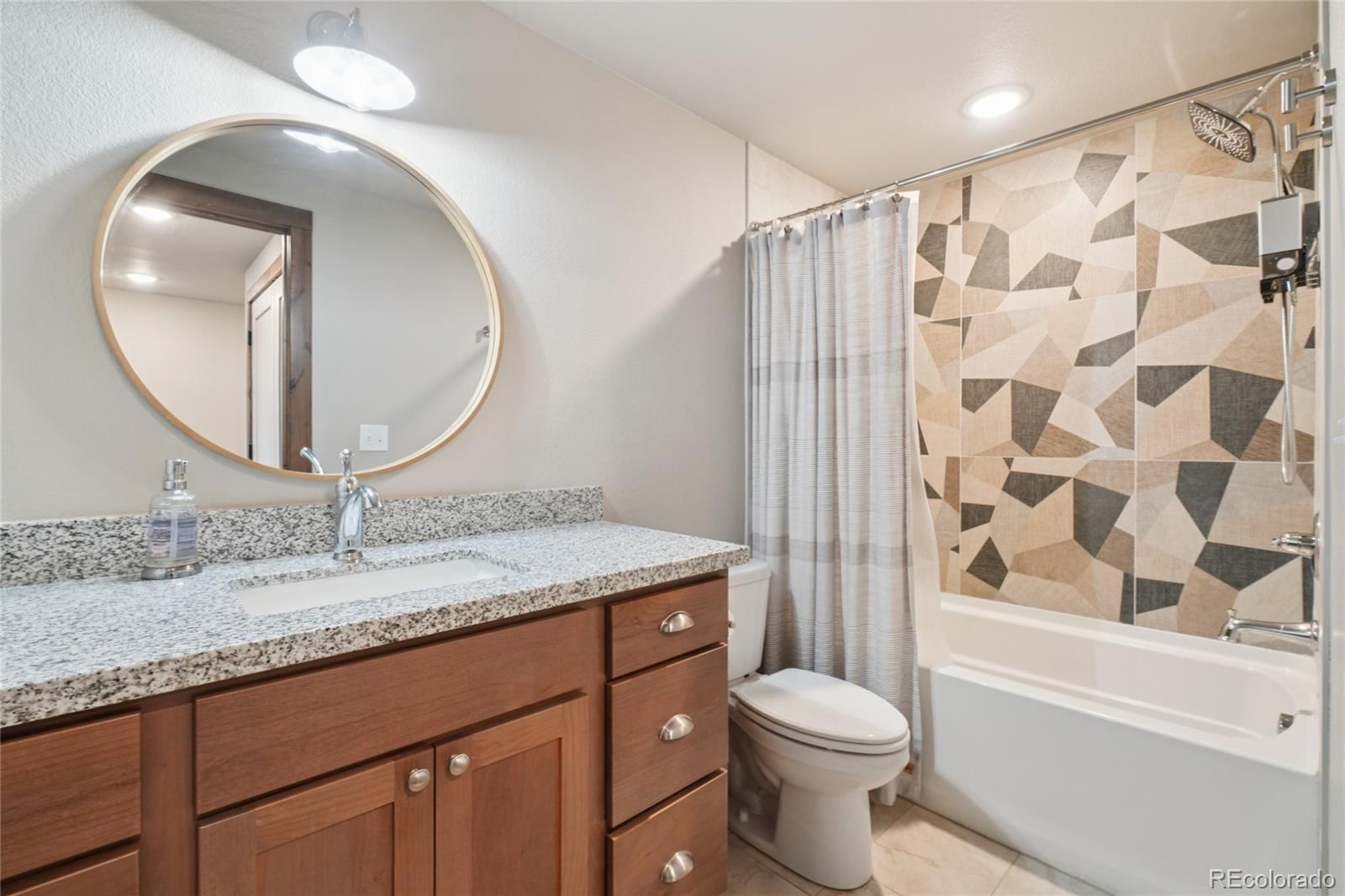 1700 Wildfire Road, Unit 301 Estes Park, CO 80517 - Photo 27 of 38 a bathroom with a granite countertop sink toilet mirror and shower