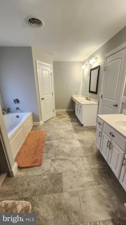 a bathroom with a tub sink and mirror
