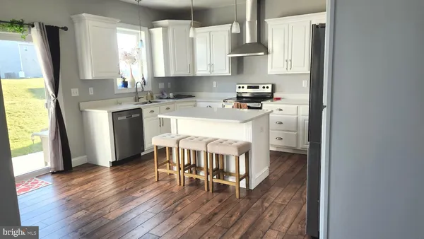 a kitchen with stainless steel appliances a dining table chairs a refrigerator and a sink