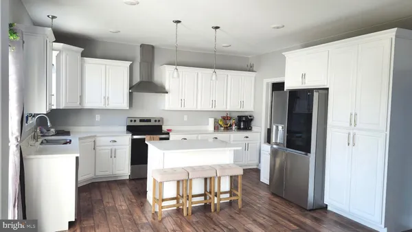 a kitchen with stainless steel appliances a refrigerator a stove a sink dishwasher and a refrigerator with wooden floor