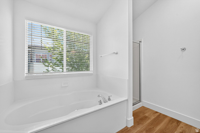 14771 Haddington Road Draper, UT 84020 - Photo 21 of 44 Soaking tub with chrome fixtures, large window with blinds, and wood-finish flooring