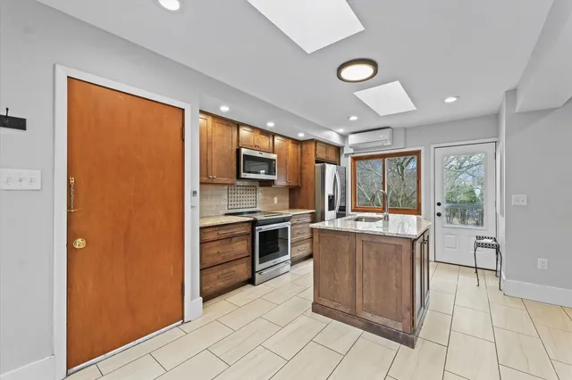 a kitchen with stainless steel appliances granite countertop a stove top oven a refrigerator and a sink
