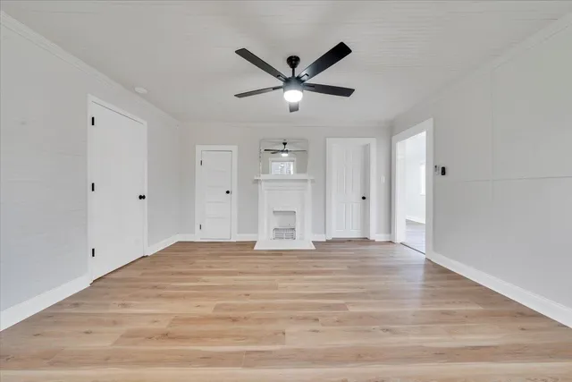 a view of an empty room with window and ceiling fan