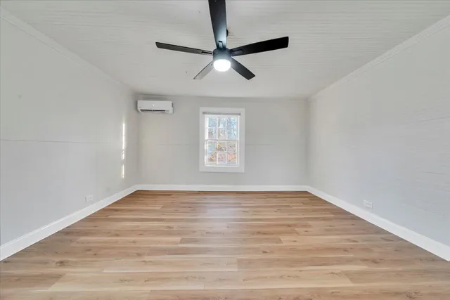 a view of empty room with wooden floor and fan