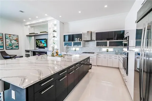 a large kitchen with a large counter top a sink stainless steel appliances and cabinets