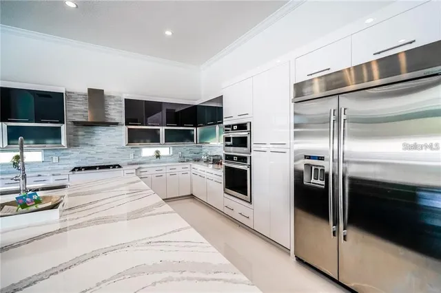 a kitchen with stainless steel appliances kitchen island granite countertop a stove a refrigerator and a sink