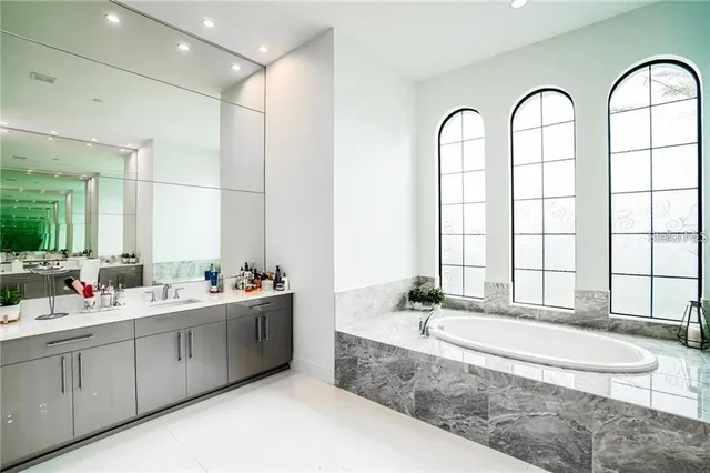 a spacious bathroom with a double vanity sink a mirror and a bathtub