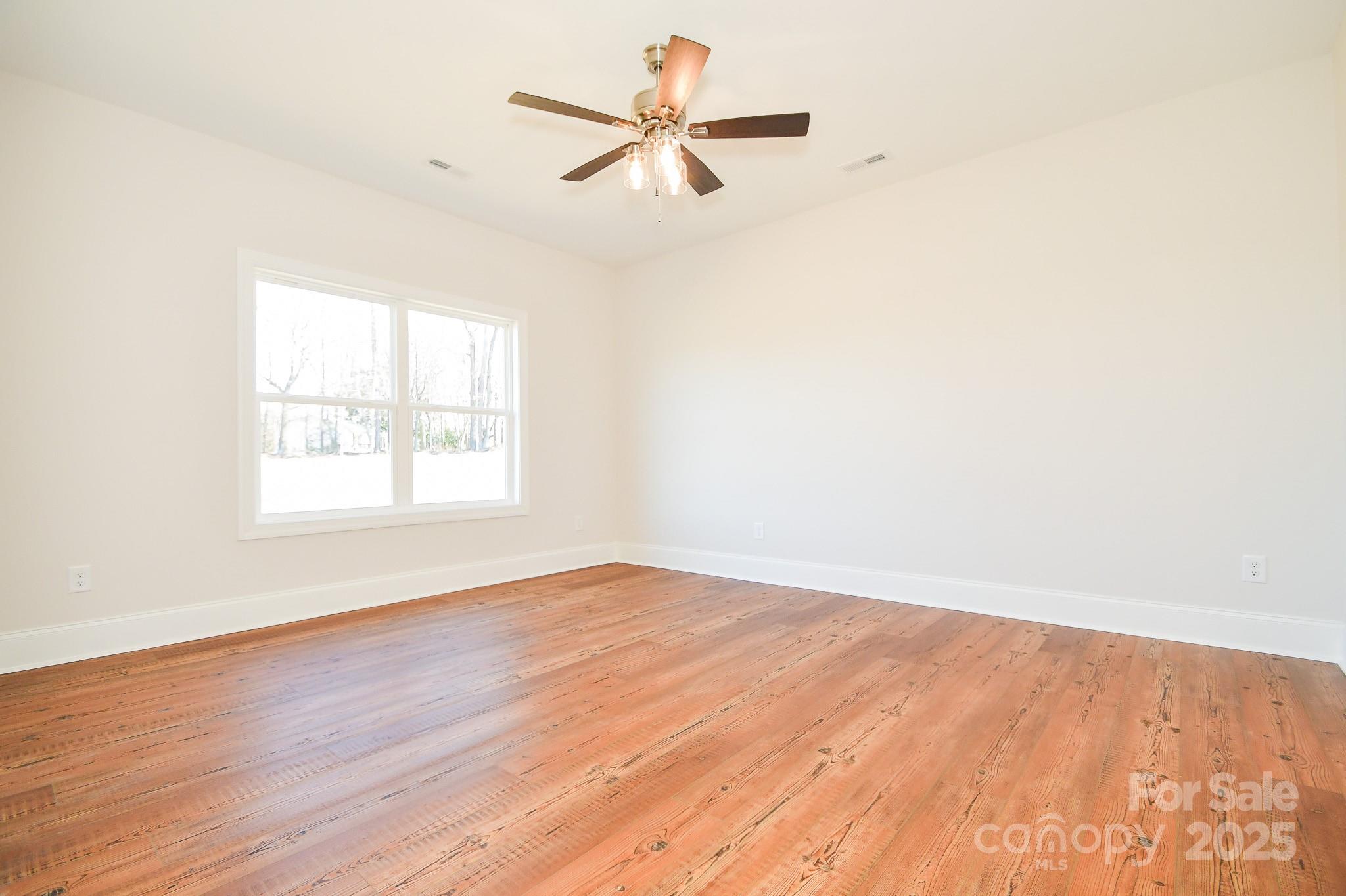 7805 Medlin Road Monroe, NC 28112 - Photo 8 of 13 an empty room with wooden floor fan and windows