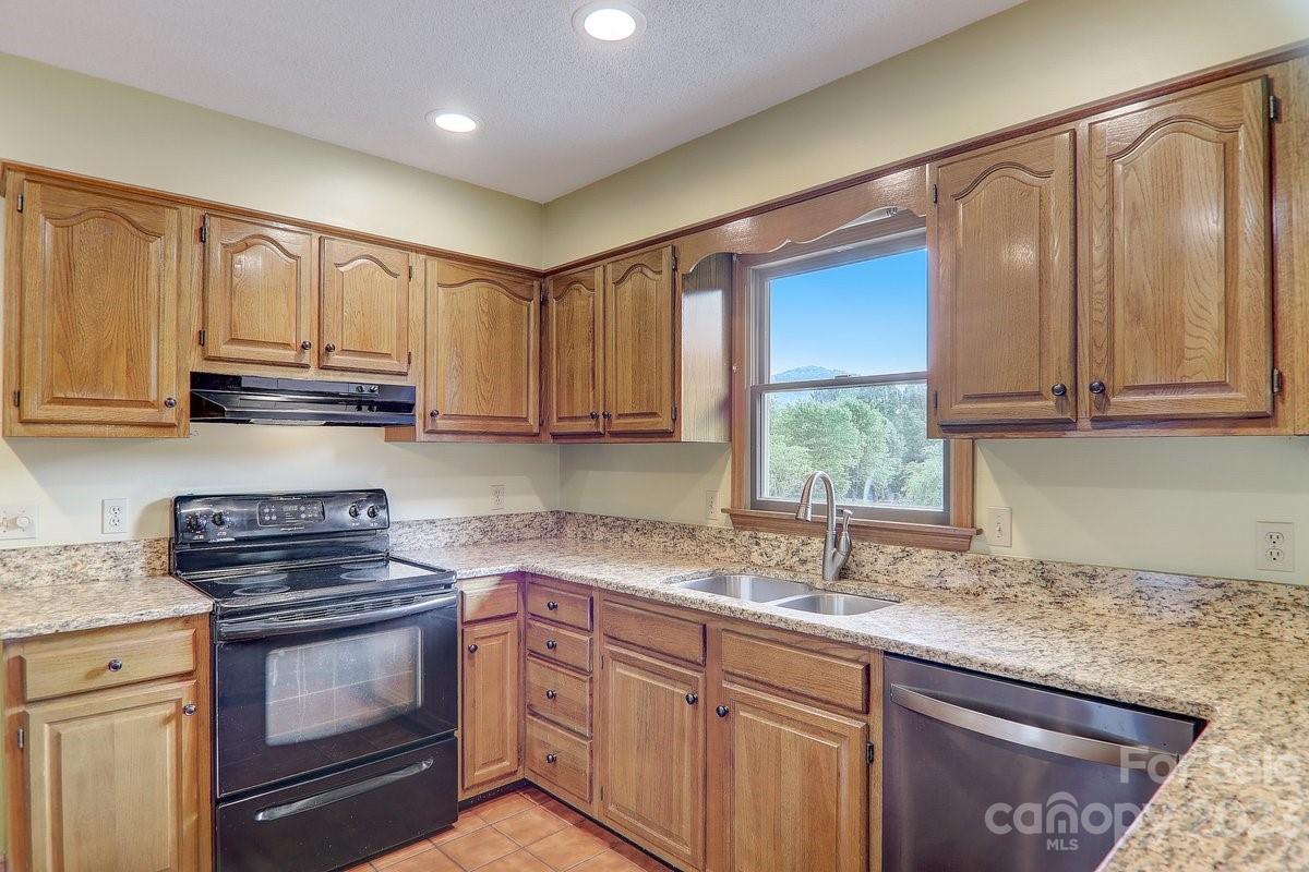 110 Oak Hill Road Candler, NC 28715 - Photo 13 of 37 a kitchen with granite countertop a sink cabinets stainless steel appliances and a window