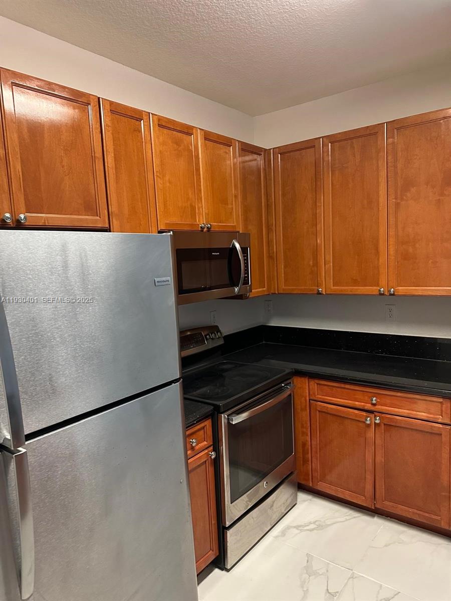 12421 Southwest 50th Court, Unit 337 Miramar, FL 33027 - Photo 7 of 46 a kitchen with granite countertop a refrigerator and a sink