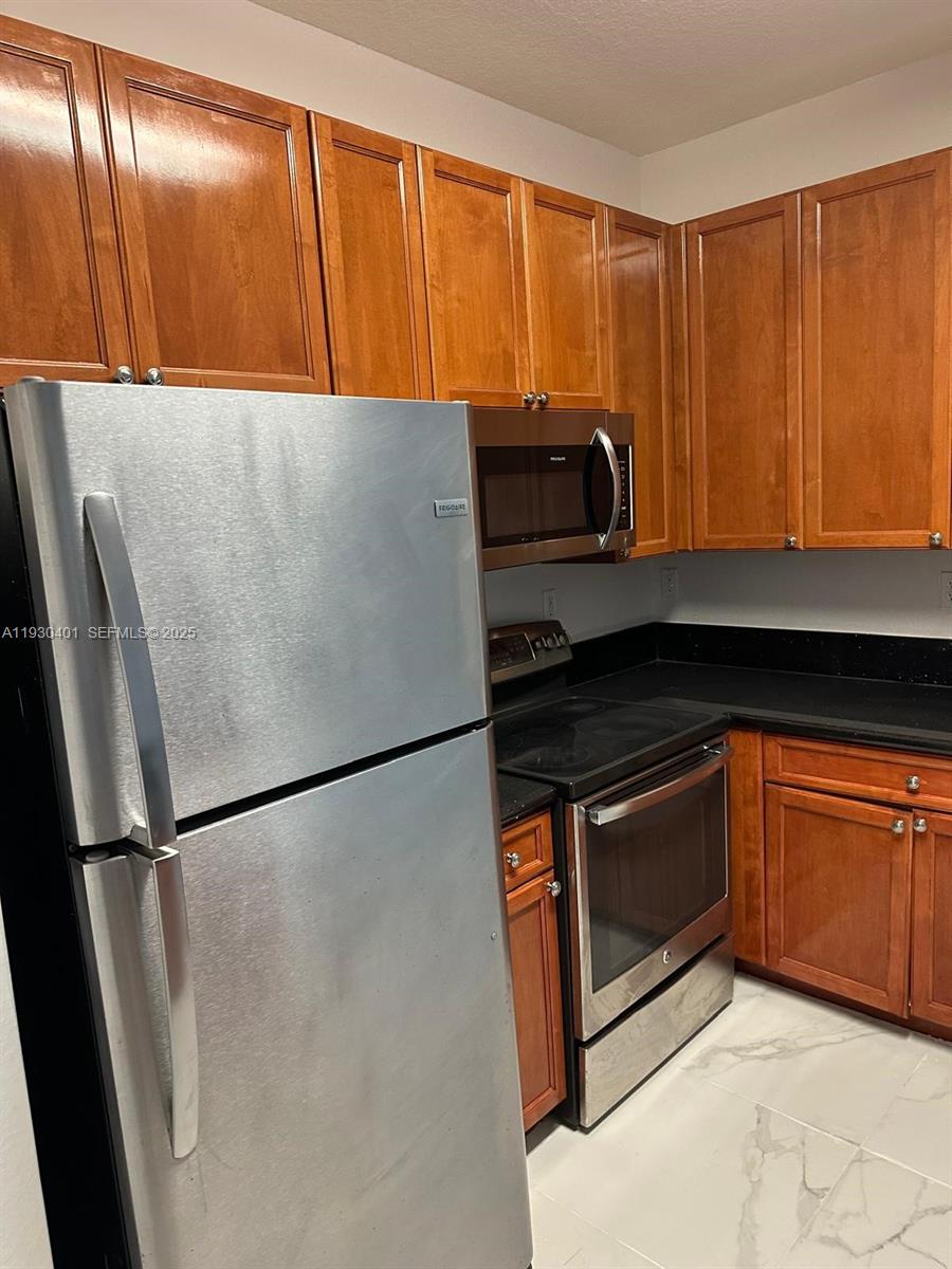 12421 Southwest 50th Court, Unit 337 Miramar, FL 33027 - Photo 8 of 46 a kitchen with granite countertop a refrigerator and a sink