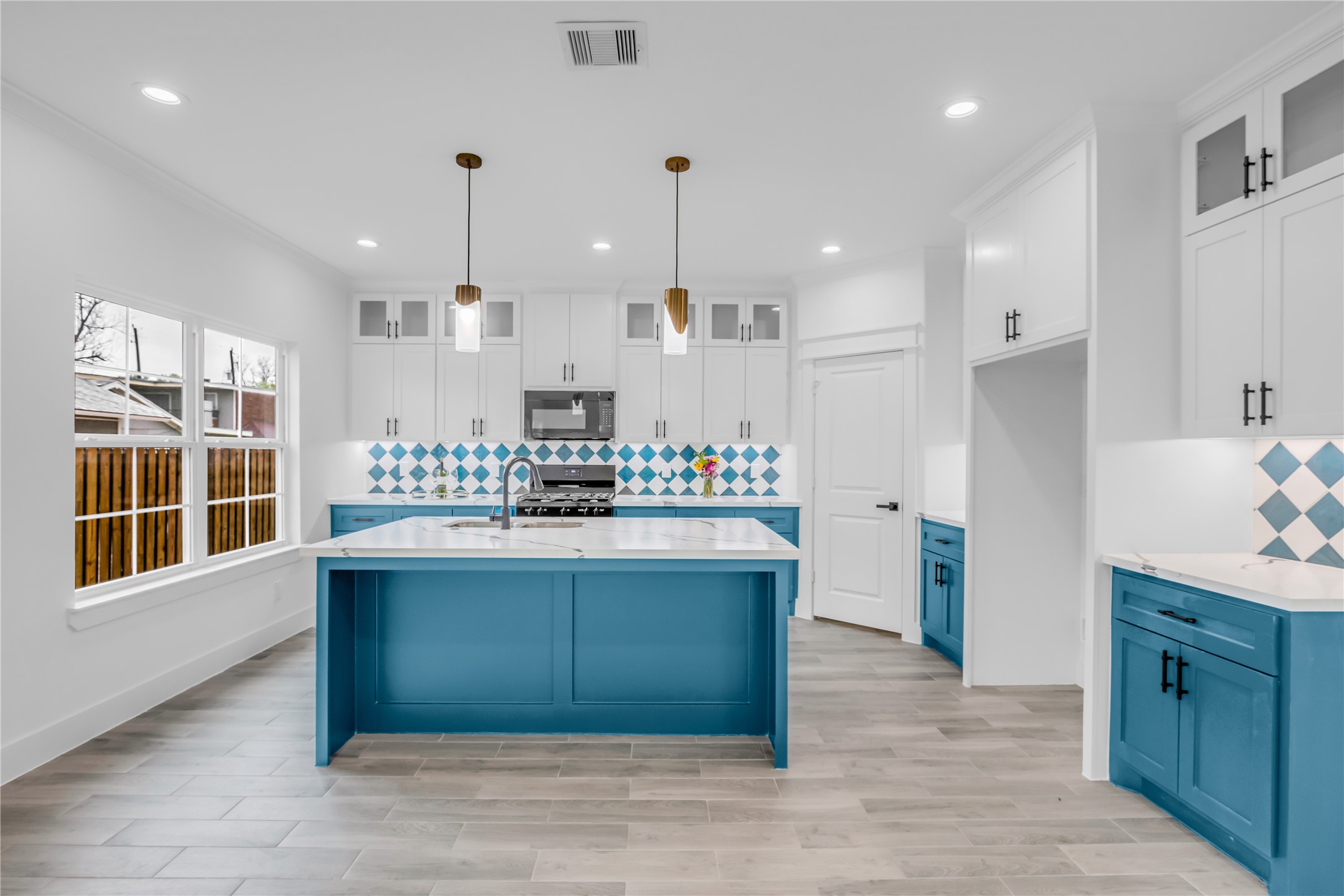 3168 Golfcrest Houston, TX 77087 - Photo 6 of 30 Discover a bright, modern kitchen with striking blue cabinetry, elegant white countertops, and eye-catching patterned backsplash, perfect for culinary creativity and entertaining.