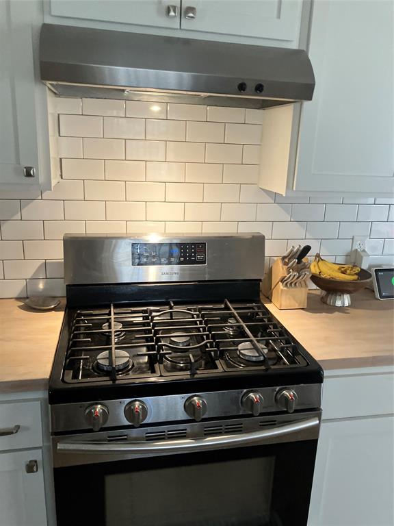 233 Church Road Stonewall, LA 71078 - Photo 21 of 32 Kitchen view of extractor fan, gas range oven, light countertops, backsplash, and white cabinets