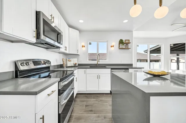 a kitchen with granite countertop white cabinets stainless steel appliances and a counter space
