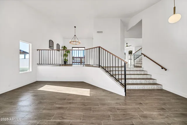 an empty room with wooden floor a ceiling fan and windows