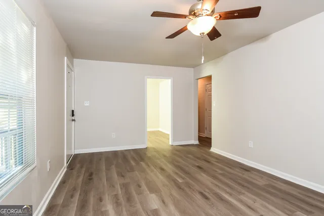 a view of empty room with wooden floor and fan