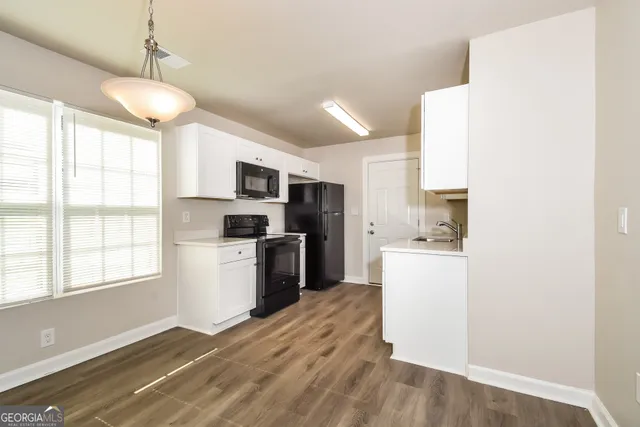 a kitchen with a refrigerator a stove top oven a sink dishwasher and white cabinets with wooden floor