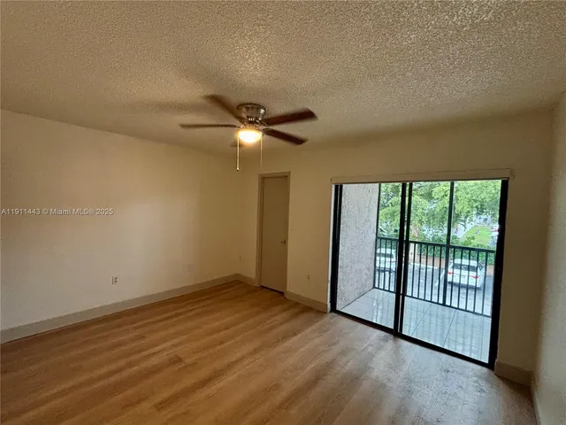 an empty room with wooden floor fan and windows