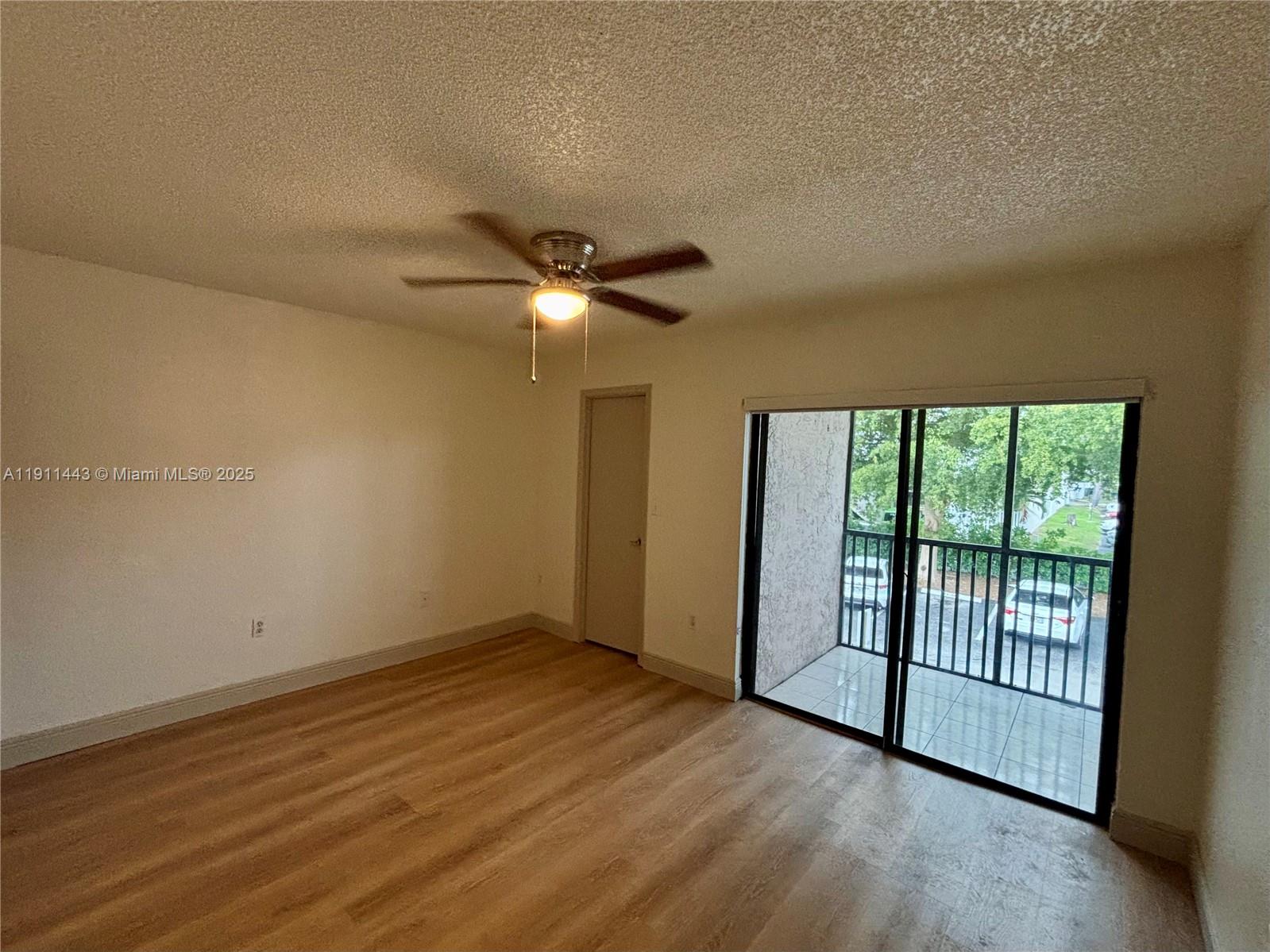10350 Southwest 220th Street, Unit 251 Cutler Bay, FL 33190 - Photo 4 of 10 an empty room with wooden floor fan and windows