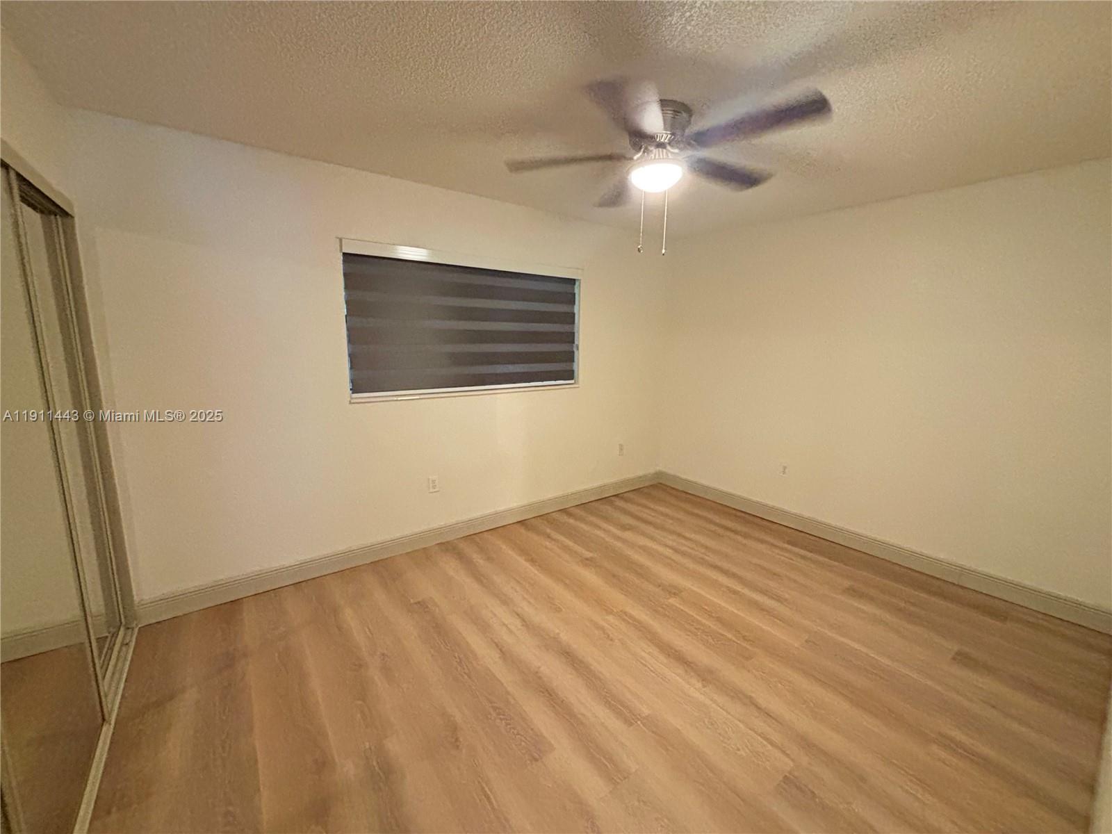 10350 Southwest 220th Street, Unit 251 Cutler Bay, FL 33190 - Photo 5 of 10 a view of an empty room with wooden floor and a window