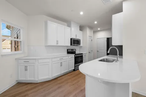 a kitchen with sink a microwave and cabinets