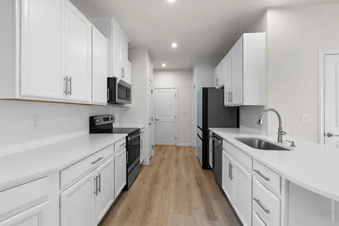 a kitchen with stainless steel appliances granite countertop white cabinets sink and stove