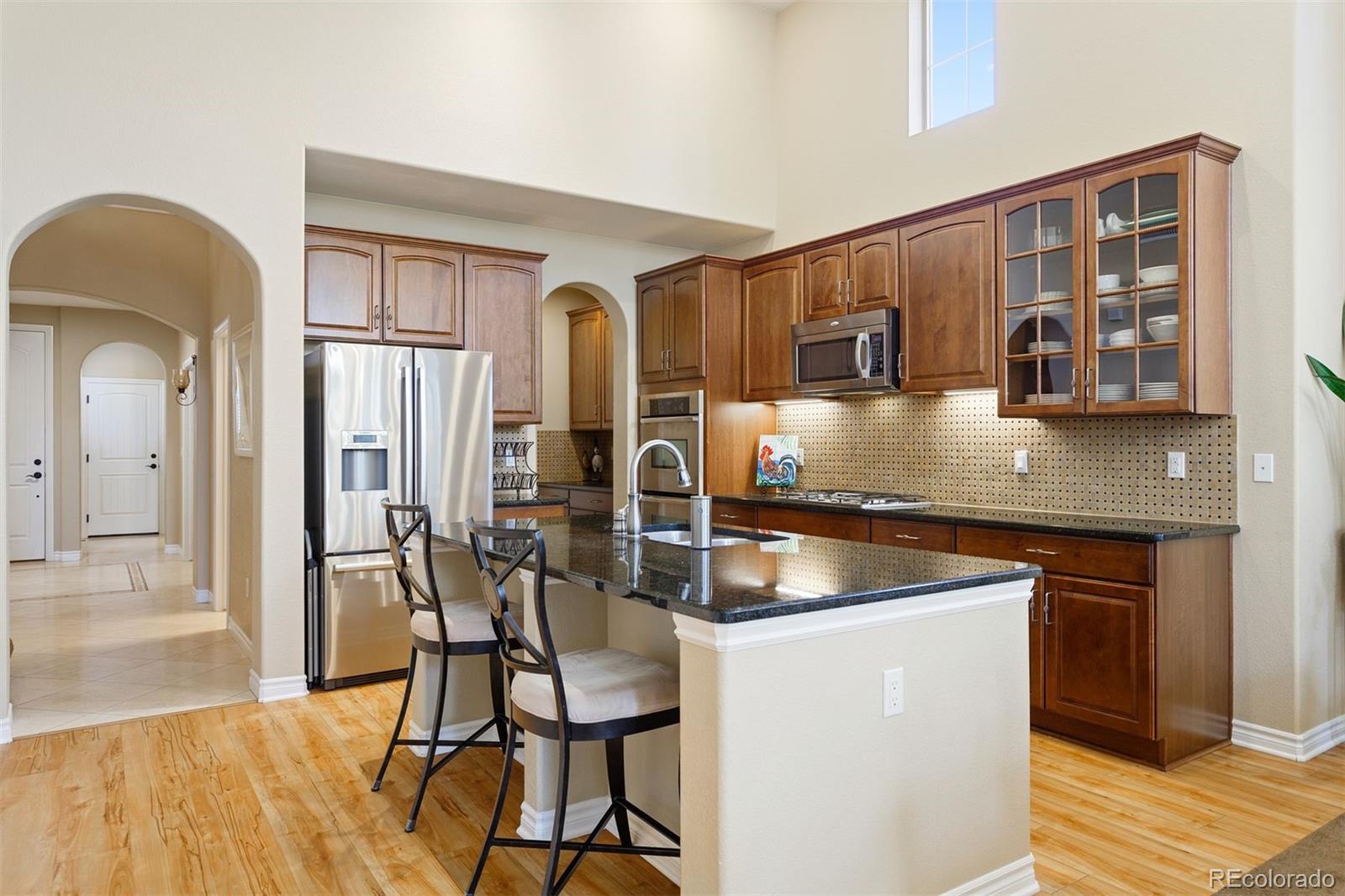 9236 Viaggio Way Highlands Ranch, CO 80126 - Photo 11 of 41 a kitchen with stainless steel appliances granite countertop a table chairs in it and wooden floors