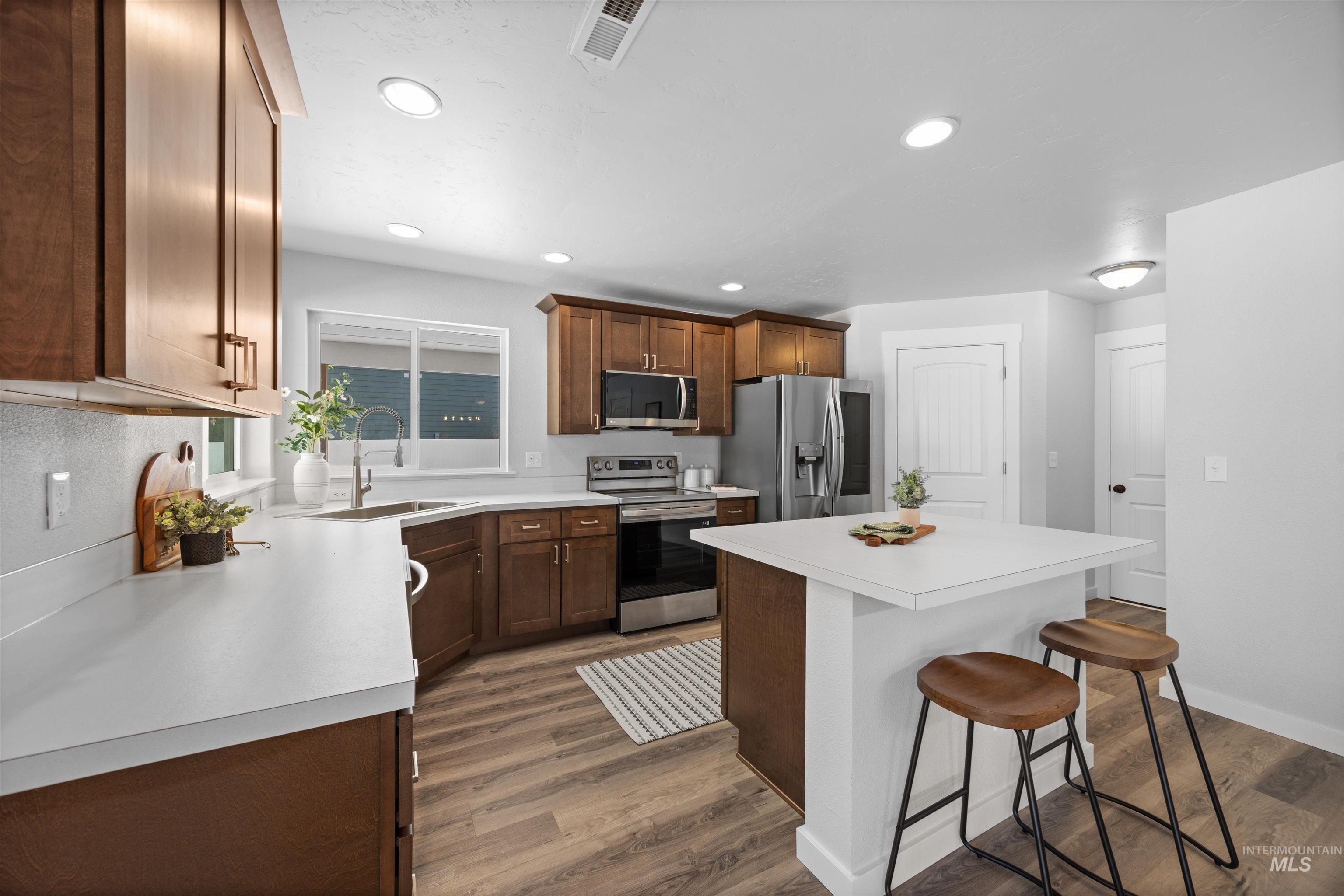 300 South Rocker Avenue Kuna, ID 83634 - Photo 15 of 49 Kitchen featuring wood-finish cabinetry, stainless steel appliances, a center island with counter seating, and recessed lighting