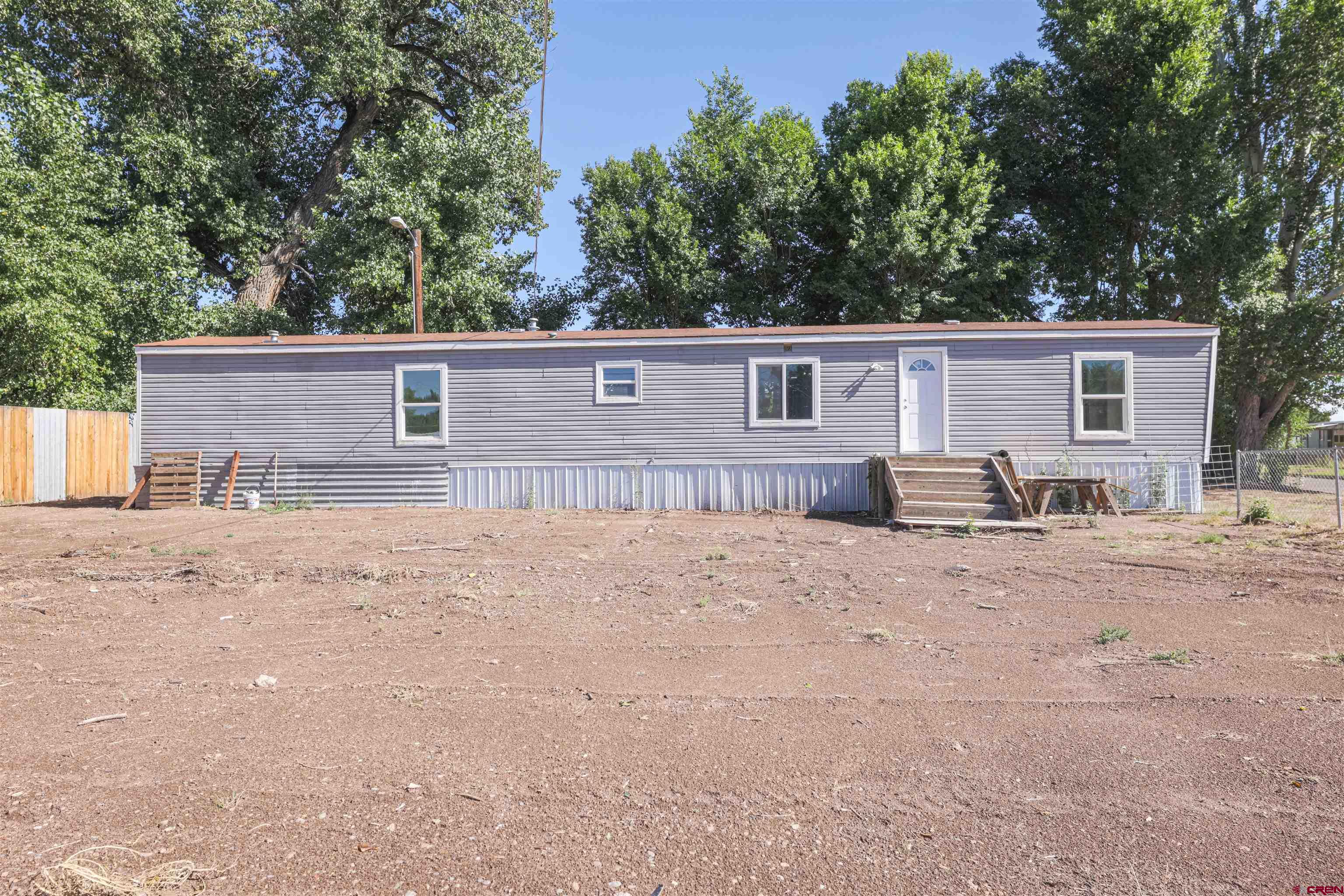 a backyard of a house with wooden fence and large trees