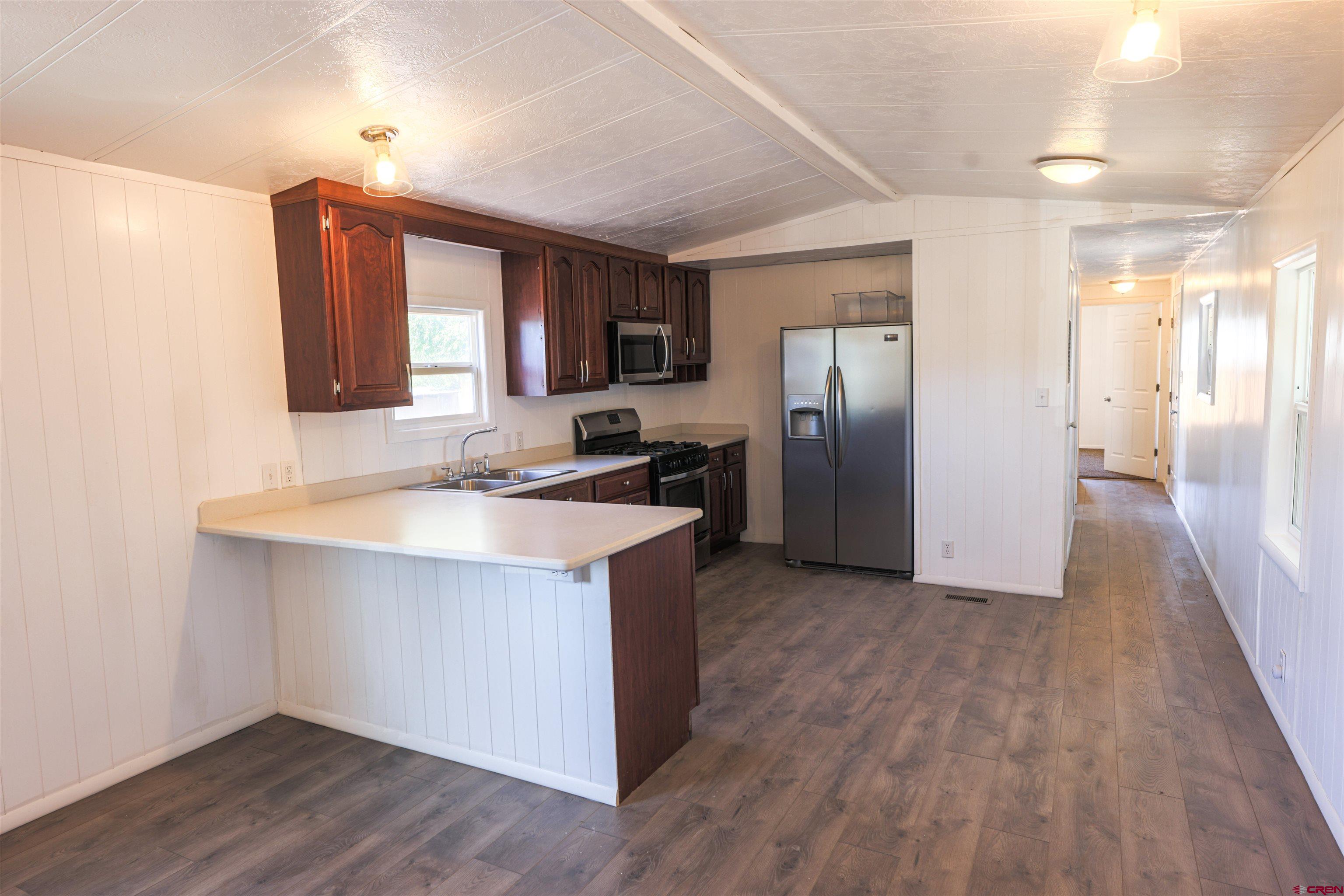 11 Rickey Place Monte Vista, CO 81144 - Photo 3 of 20 a kitchen with stainless steel appliances granite countertop a sink a refrigerator and wooden floor