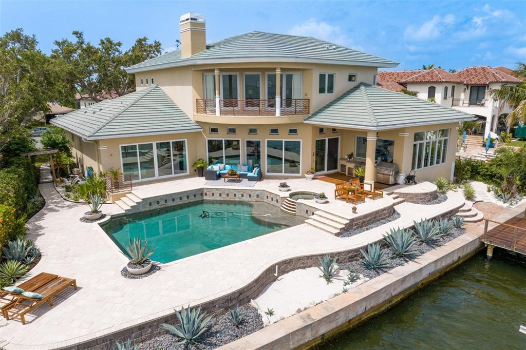 a view of a patio with couches chairs and swimming pool with a barbeque grill