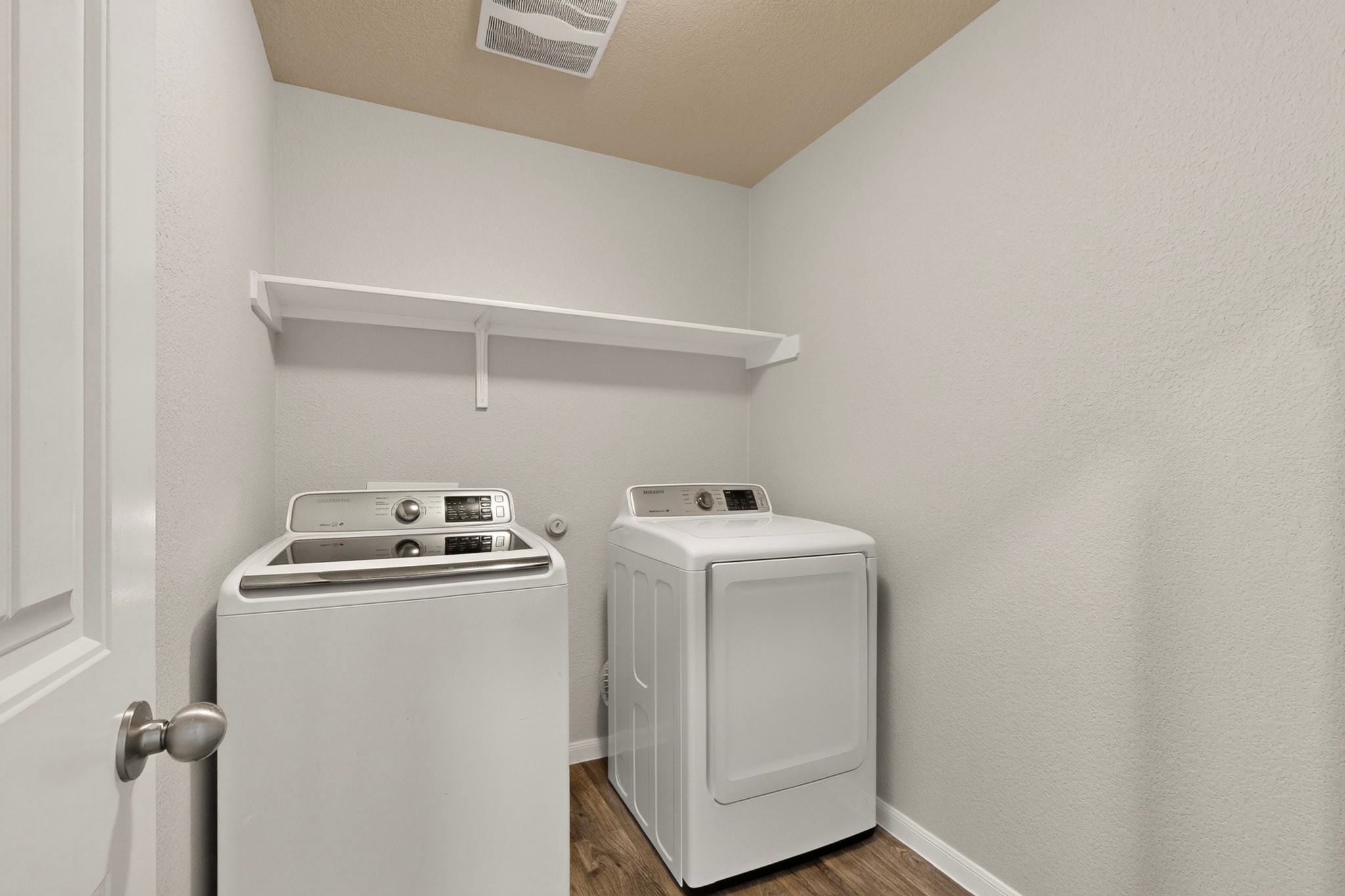 11612 Andesite Road Manor, TX 78653 - Photo 10 of 40 Functional laundry setup highlights wood-look flooring and a built-in shelf over the appliances.